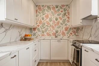 Cuisine entièrement blanche réchauffée par un panneau de tapisserie lavable à motifs botaniques en teintes terracotta et vert sauge